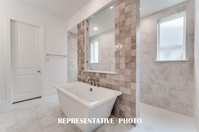 bathroom with tile walls, independent shower and bath, and a healthy amount of sunlight