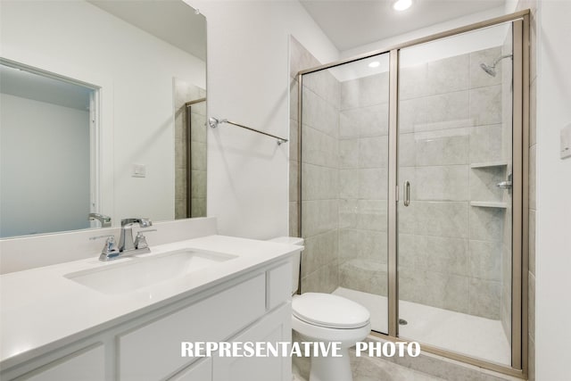 bathroom with toilet, vanity, and a shower with shower door