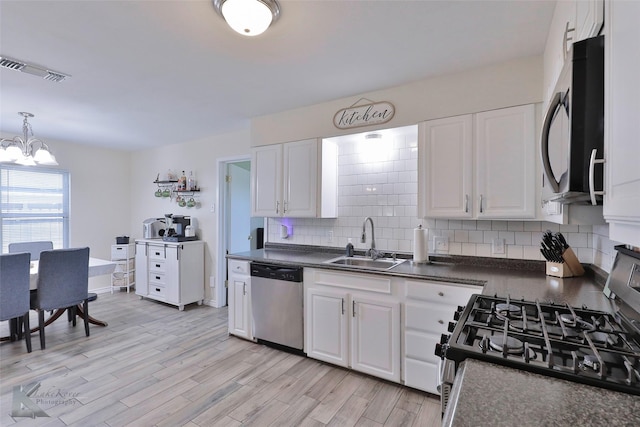 kitchen featuring an inviting chandelier, appliances with stainless steel finishes, backsplash, white cabinets, and sink