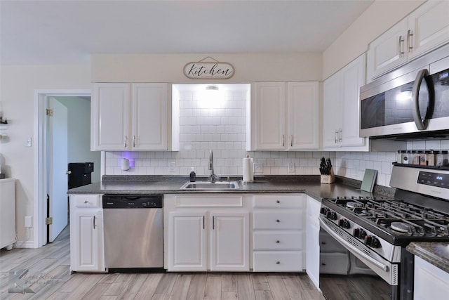 kitchen featuring stainless steel appliances, backsplash, white cabinets, and sink