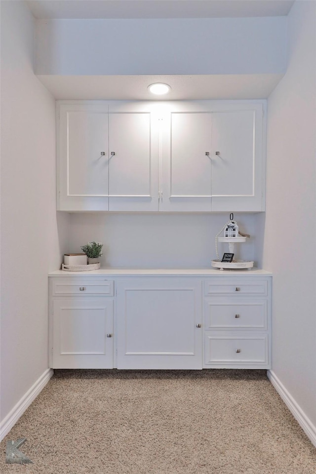 bar featuring light colored carpet and white cabinetry