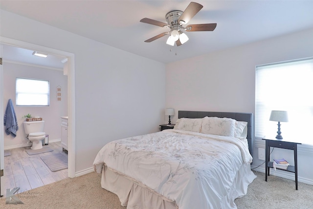 bedroom featuring ceiling fan, ensuite bath, and light wood-type flooring