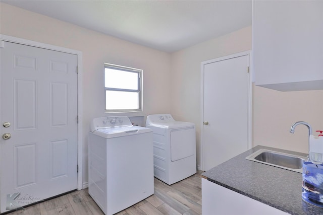 clothes washing area with sink, washing machine and dryer, and light wood-type flooring