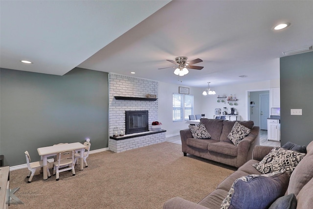 living room with a fireplace, carpet flooring, and ceiling fan with notable chandelier