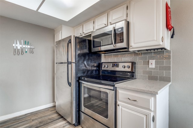 kitchen featuring hardwood / wood-style flooring, stainless steel appliances, backsplash, and white cabinetry