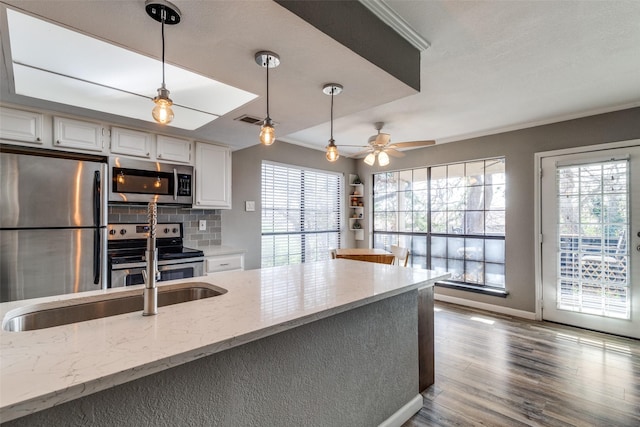 kitchen featuring white cabinets, stainless steel appliances, decorative backsplash, sink, and light stone counters