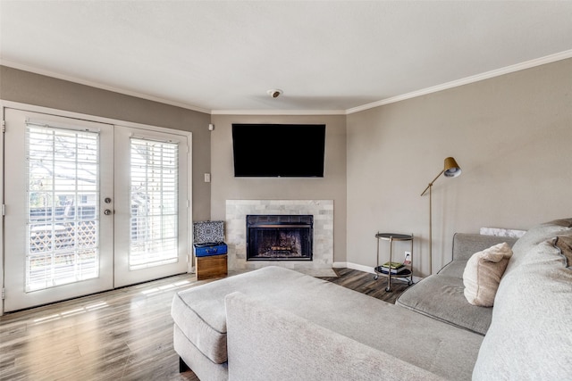 living room with french doors, a tile fireplace, crown molding, and hardwood / wood-style floors