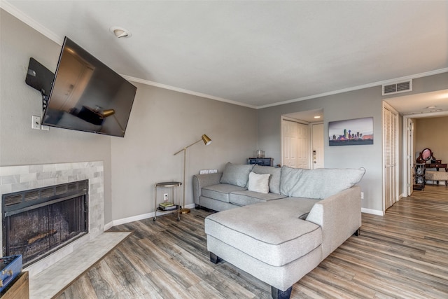 living room with wood-type flooring, a fireplace, and ornamental molding