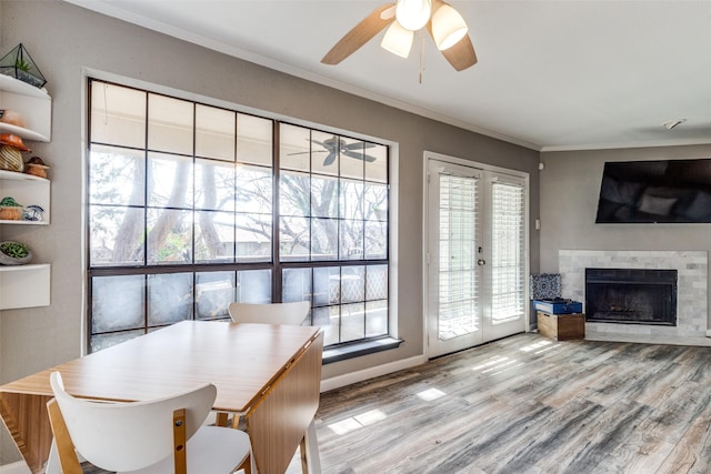 dining space featuring ceiling fan, a wealth of natural light, a fireplace, french doors, and ornamental molding