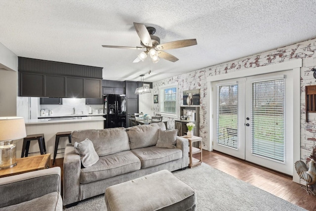 living room with hardwood / wood-style flooring, ceiling fan, a textured ceiling, and french doors