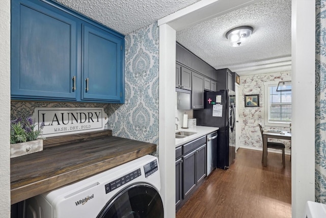 kitchen with dishwasher, washer / dryer, sink, blue cabinets, and dark hardwood / wood-style flooring