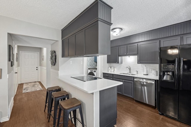 kitchen with gray cabinets, black appliances, a breakfast bar, kitchen peninsula, and sink