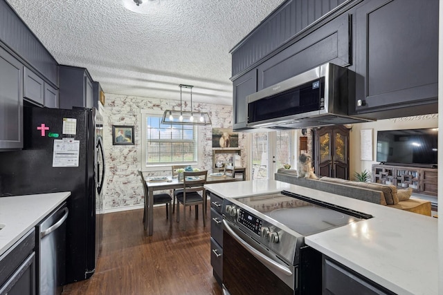 kitchen featuring pendant lighting, appliances with stainless steel finishes, dark hardwood / wood-style flooring, and a textured ceiling