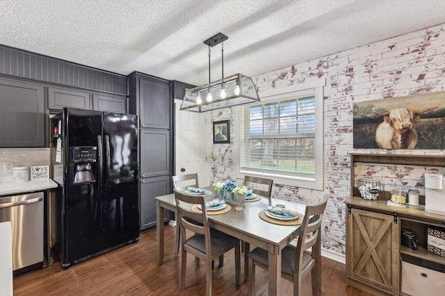 dining area with brick wall, dark wood-type flooring, and a textured ceiling