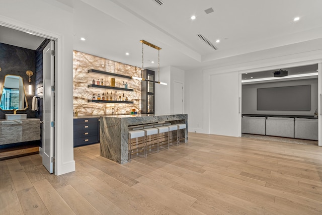 bar featuring sink, light hardwood / wood-style floors, and decorative light fixtures