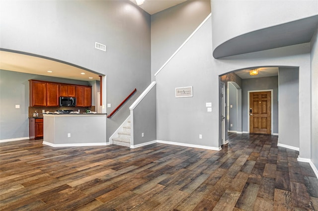 unfurnished living room with a high ceiling and dark wood-type flooring