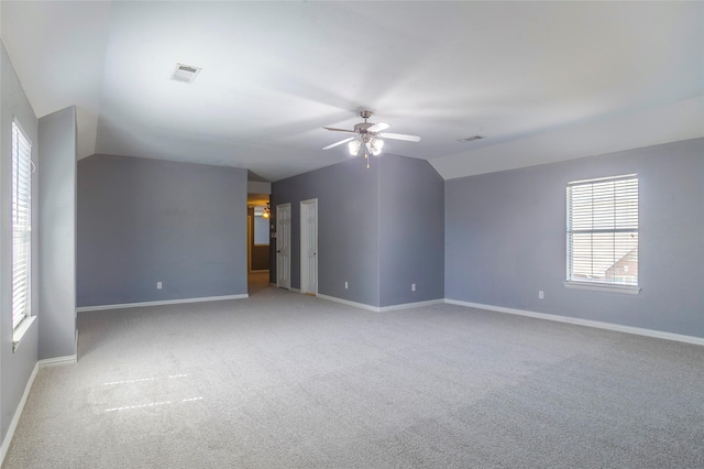 carpeted spare room featuring ceiling fan, a healthy amount of sunlight, and vaulted ceiling