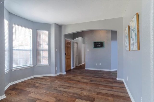 empty room with dark hardwood / wood-style flooring and plenty of natural light