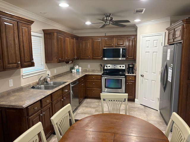 kitchen featuring light tile patterned floors, ceiling fan, appliances with stainless steel finishes, crown molding, and sink