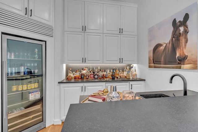 bar with white cabinetry, light hardwood / wood-style floors, high quality fridge, wine cooler, and sink