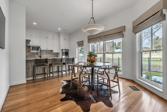 dining room with visible vents, baseboards, a healthy amount of sunlight, and light wood finished floors