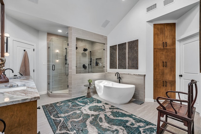 bathroom with independent shower and bath, lofted ceiling, and vanity