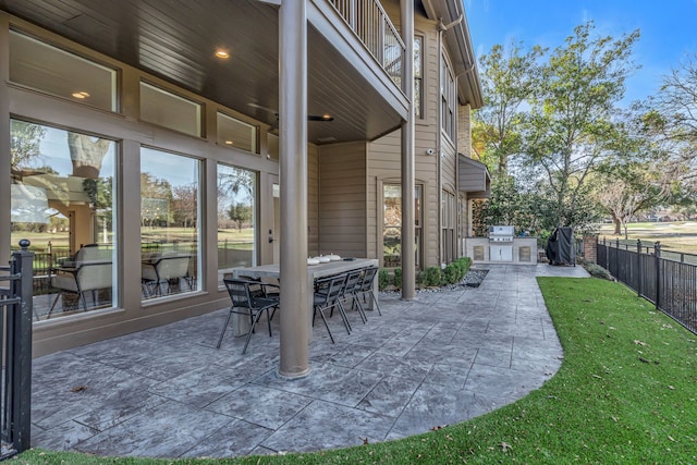 view of patio / terrace featuring a grill, outdoor dining area, fence, and an outdoor kitchen