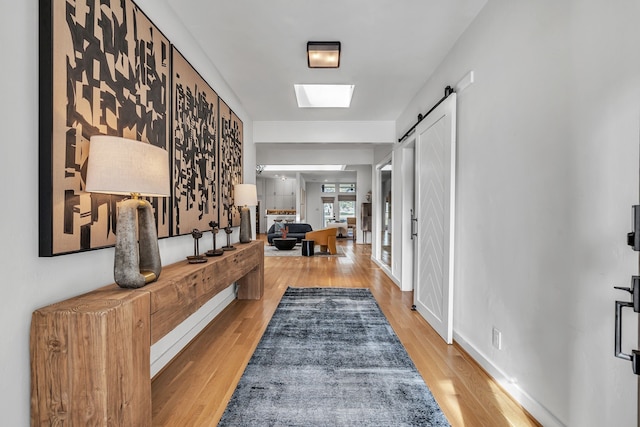 corridor featuring a skylight, a barn door, and hardwood / wood-style floors