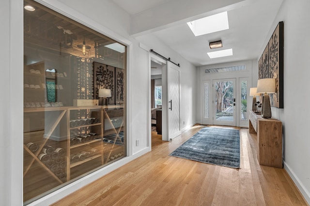 entryway featuring baseboards, a skylight, a barn door, and wood finished floors