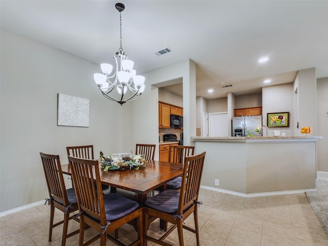 dining space featuring light tile patterned floors, sink, and an inviting chandelier