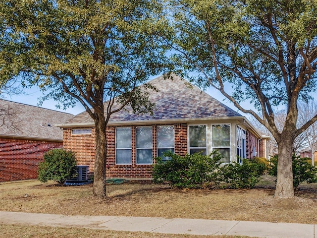 view of front of home with central AC unit and a front yard