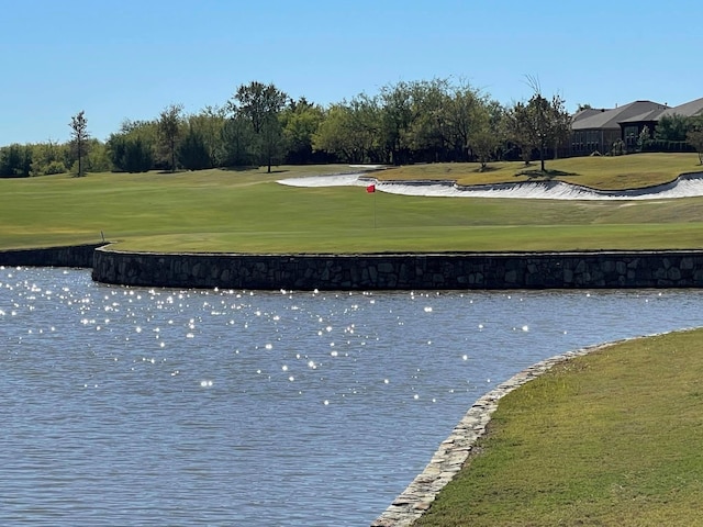 view of property's community with a lawn and a water view