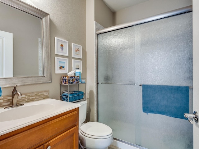 bathroom with decorative backsplash, toilet, a shower with door, and vanity