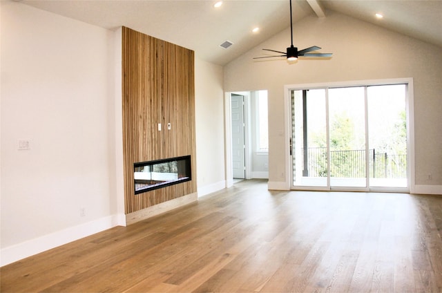 unfurnished living room featuring high vaulted ceiling, visible vents, light wood-style floors, beam ceiling, and a glass covered fireplace