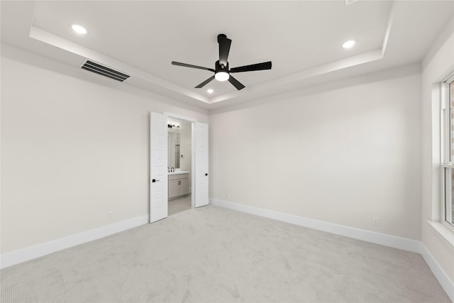 unfurnished bedroom with ceiling fan, connected bathroom, and a raised ceiling