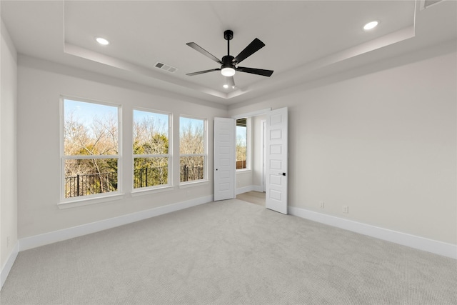 unfurnished bedroom featuring recessed lighting, light carpet, visible vents, baseboards, and a raised ceiling