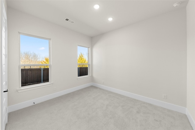 spare room with recessed lighting, plenty of natural light, visible vents, and light colored carpet