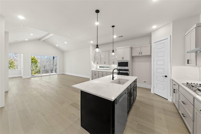 kitchen with stainless steel appliances, a sink, visible vents, an island with sink, and pendant lighting