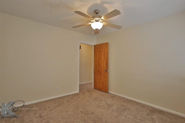 spare room with light carpet, ceiling fan, and a textured ceiling