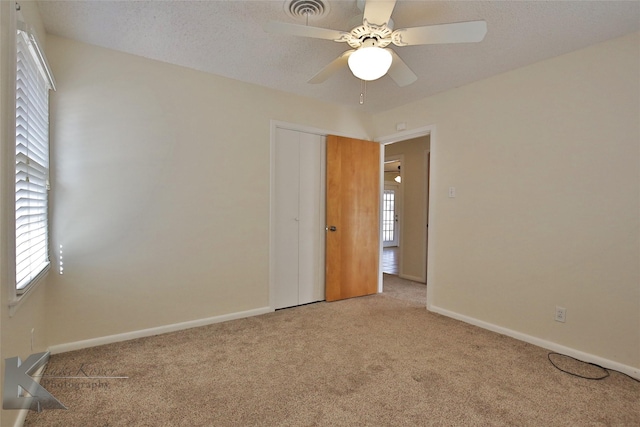 carpeted empty room with ceiling fan and a wealth of natural light