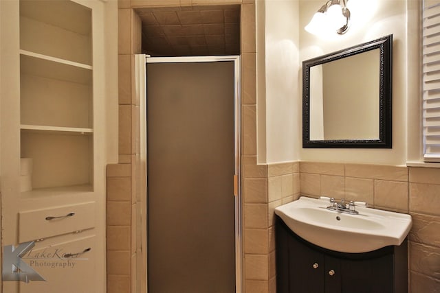 bathroom featuring built in shelves, tile walls, an enclosed shower, and vanity