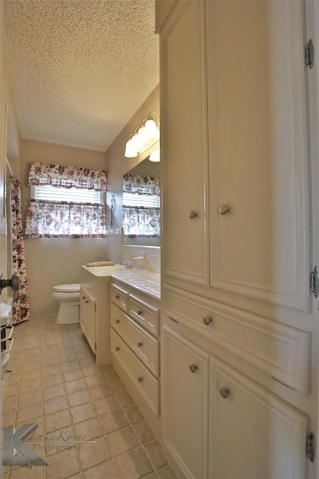 bathroom with tile patterned floors, a textured ceiling, toilet, and vanity