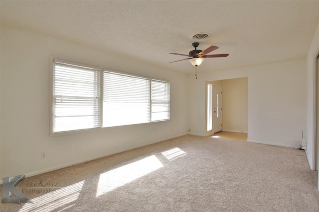 spare room with ceiling fan, a textured ceiling, and light carpet