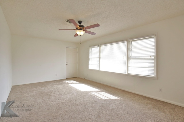 carpeted empty room with ceiling fan and a textured ceiling