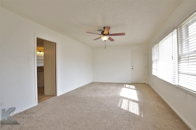 unfurnished room featuring ceiling fan, a textured ceiling, and light carpet