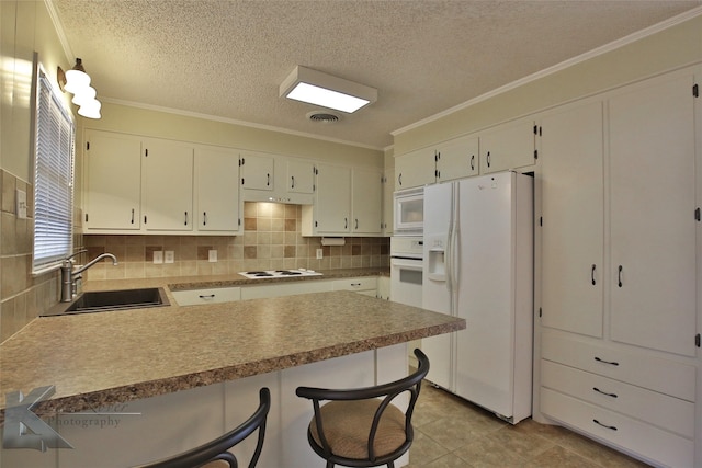 kitchen with kitchen peninsula, sink, white appliances, a breakfast bar area, and white cabinets