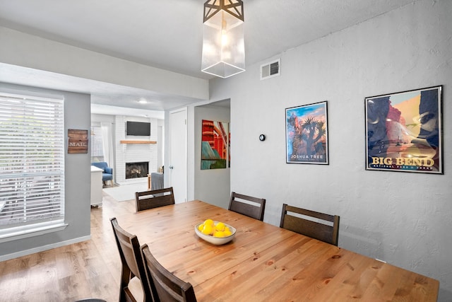 dining room with wood-type flooring and a fireplace