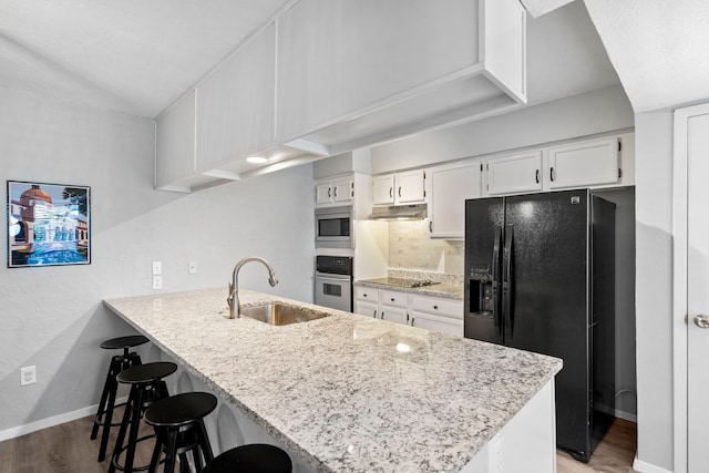 kitchen with white cabinetry, kitchen peninsula, sink, light hardwood / wood-style flooring, and black appliances