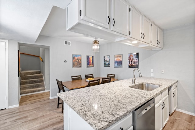 kitchen featuring dishwasher, light hardwood / wood-style floors, sink, white cabinets, and light stone counters