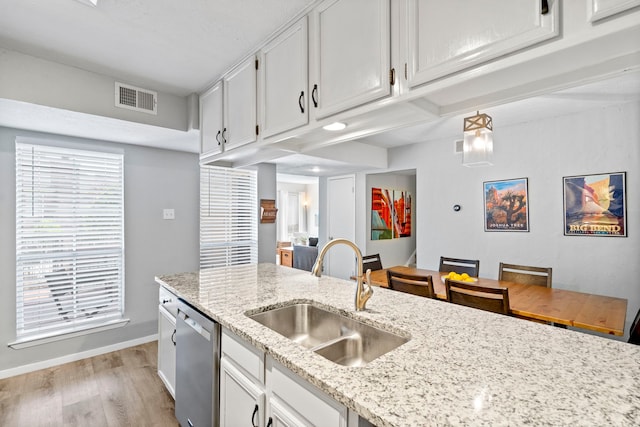 kitchen featuring white cabinetry, light wood-type flooring, stainless steel dishwasher, light stone counters, and sink